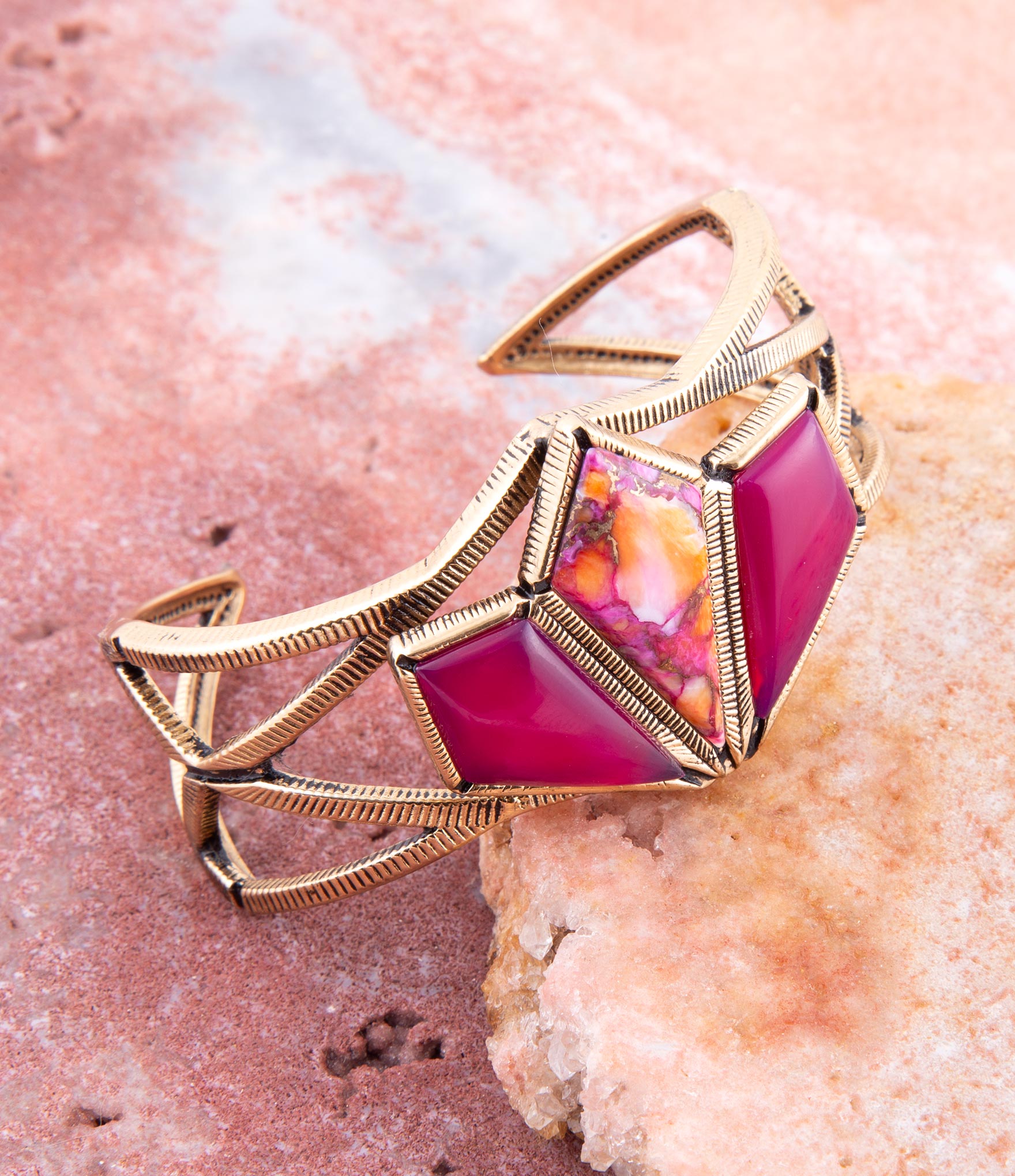 Gold bracelet with a pink gemstone on a pink stone background