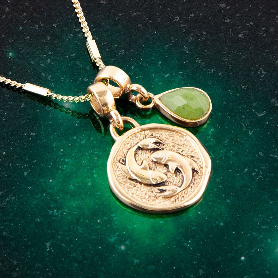 Gold necklace with a pendant featuring two dolphins on a green background
