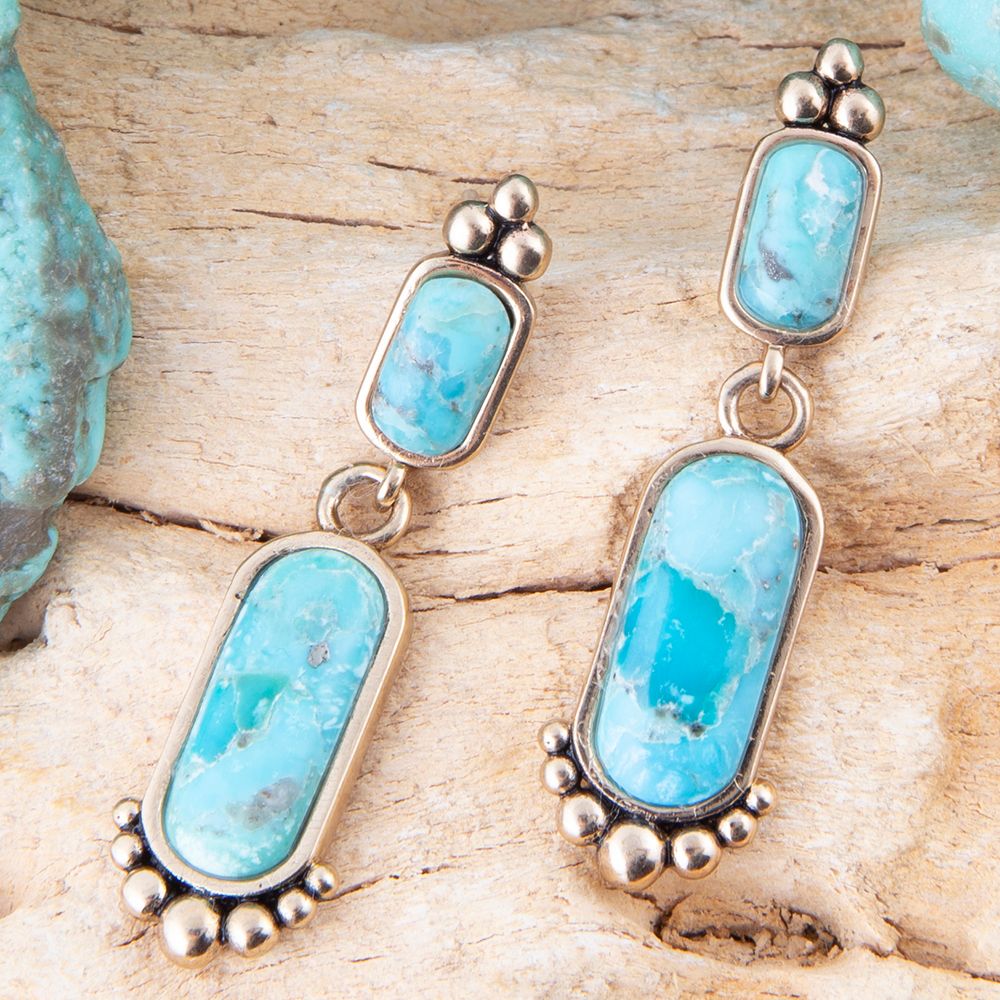 Turquoise stone earrings on a wooden surface