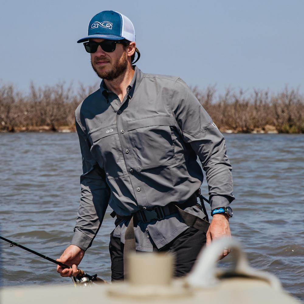 Man fishing on a boat wearing a gray shirt, black pants, and a blue cap with sunglasses.