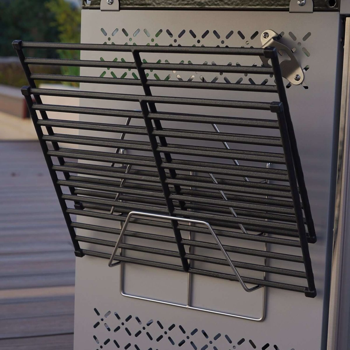 Metal grill rack attached to a barbecue grill on a wooden deck.