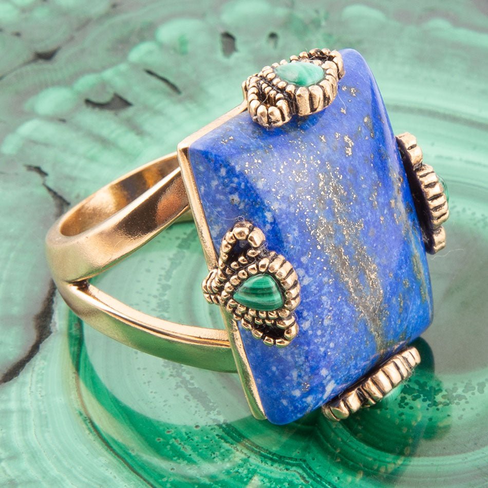 Blue stone ring with gold accents on a green textured surface