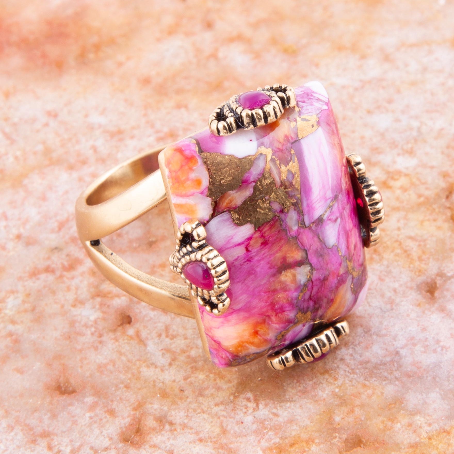 Multicolored ring with gold accents on a textured pink surface