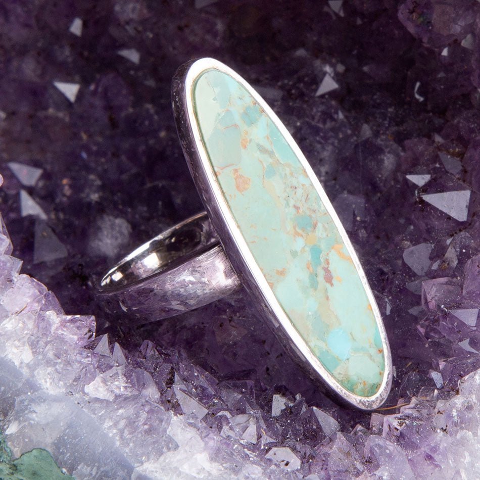 Turquoise ring with silver band on a crystal background