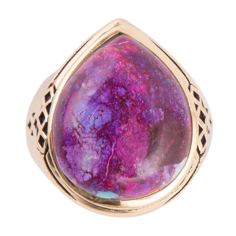 Ring with a purple and pink stone and gold band on a white background