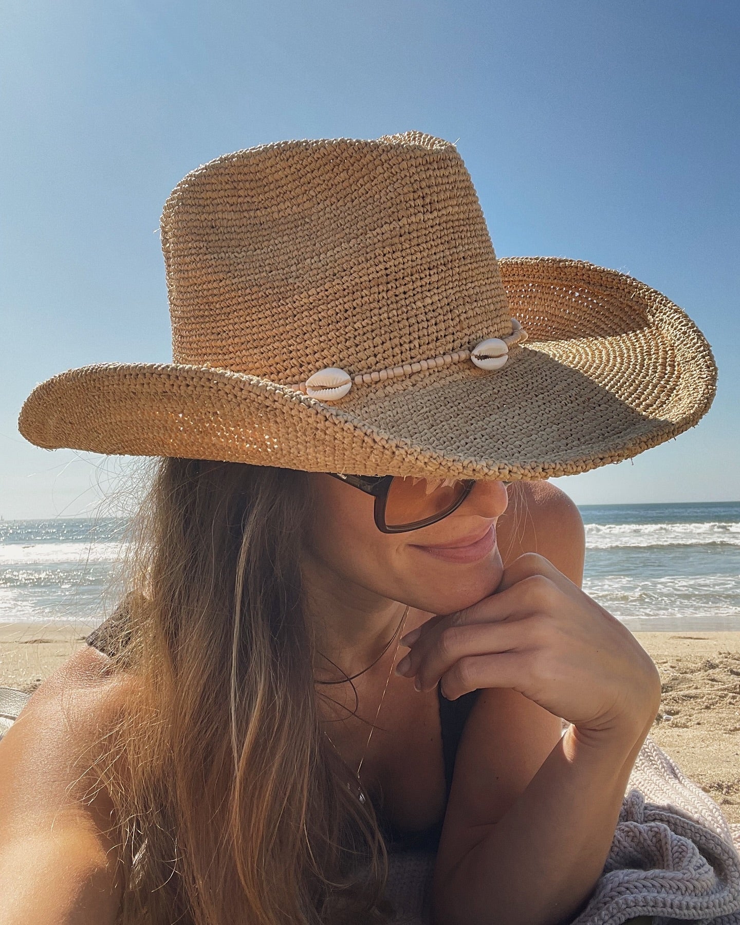 Woman wearing a straw hat on a beach with ocean view