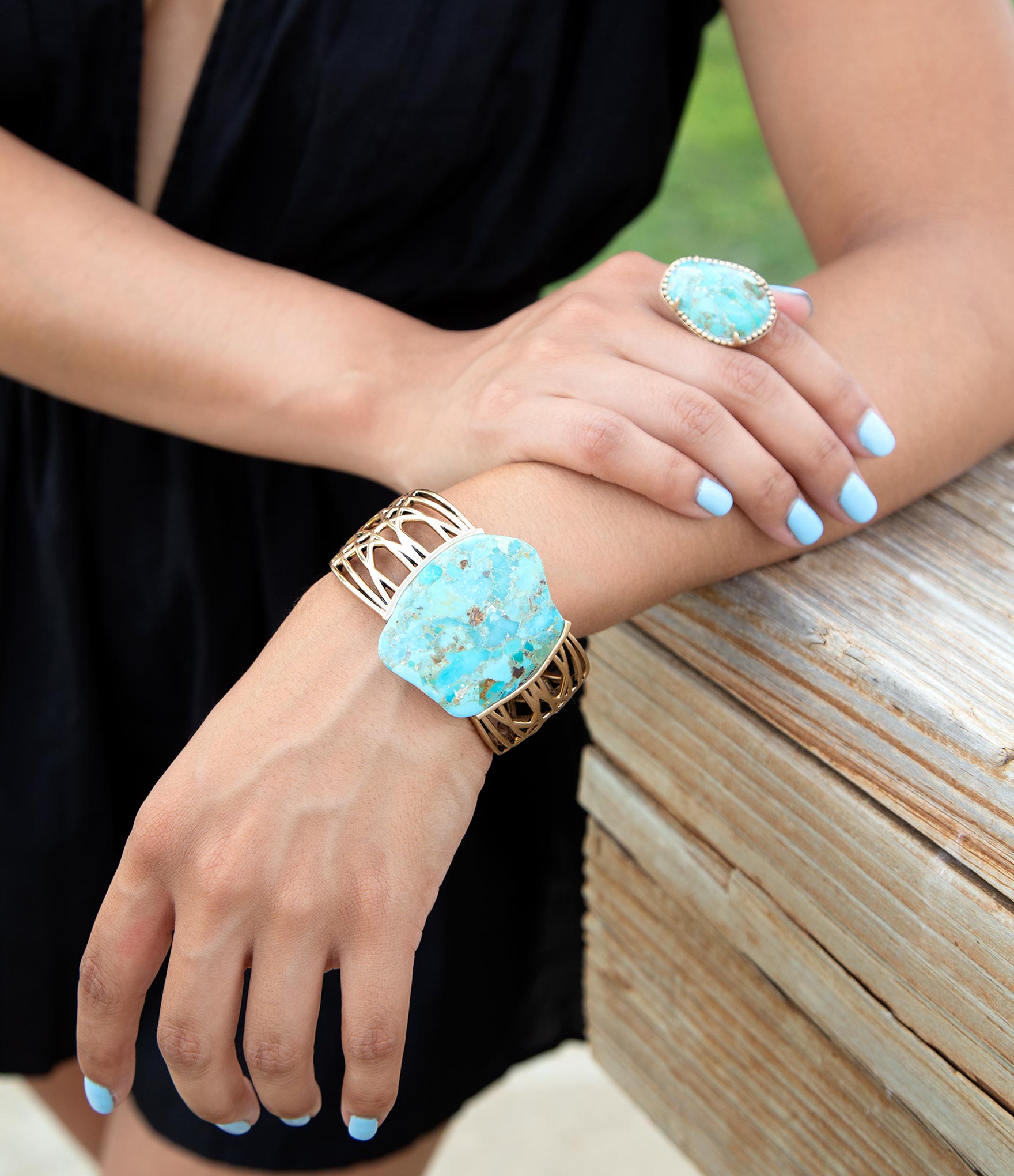 Close-up of hands wearing turquoise jewelry with a blurred natural background