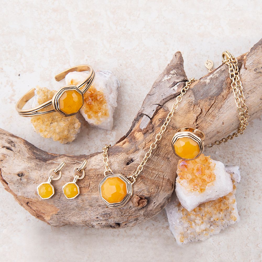 Gold jewelry set with yellow gemstones on a natural stone background