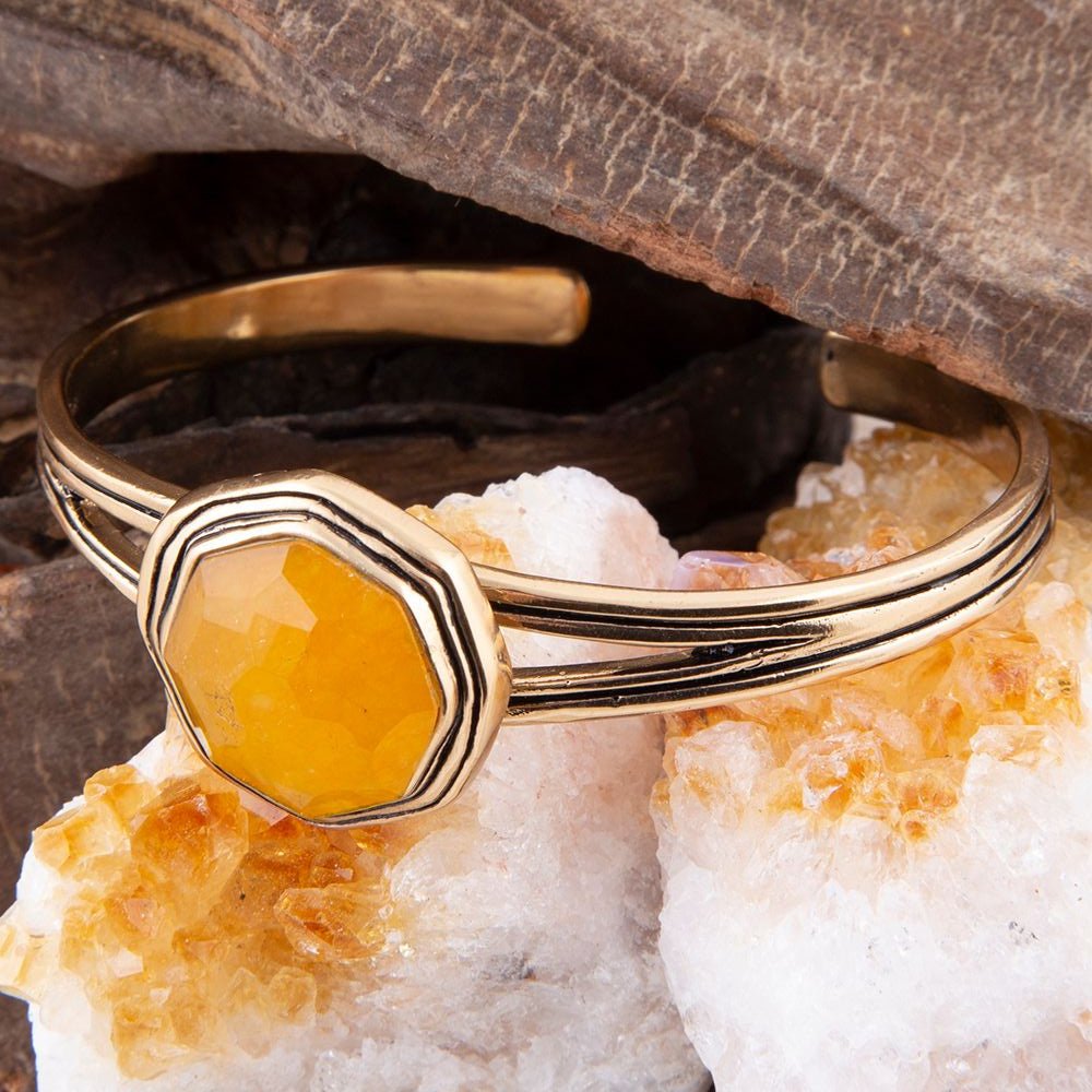 Gold bracelet with a yellow gemstone on a rock background