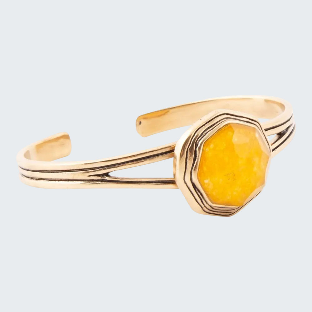 Gold bracelet with a yellow stone on a white background
