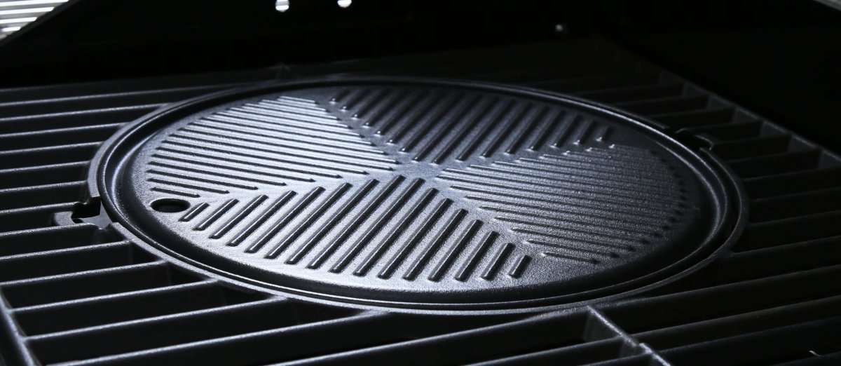 Close-up of a grill with a circular griddle plate on a black background
