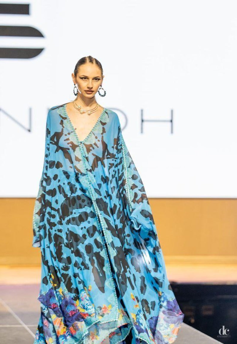 Model wearing a blue leopard print dress on a runway with 'Dior' branding.
