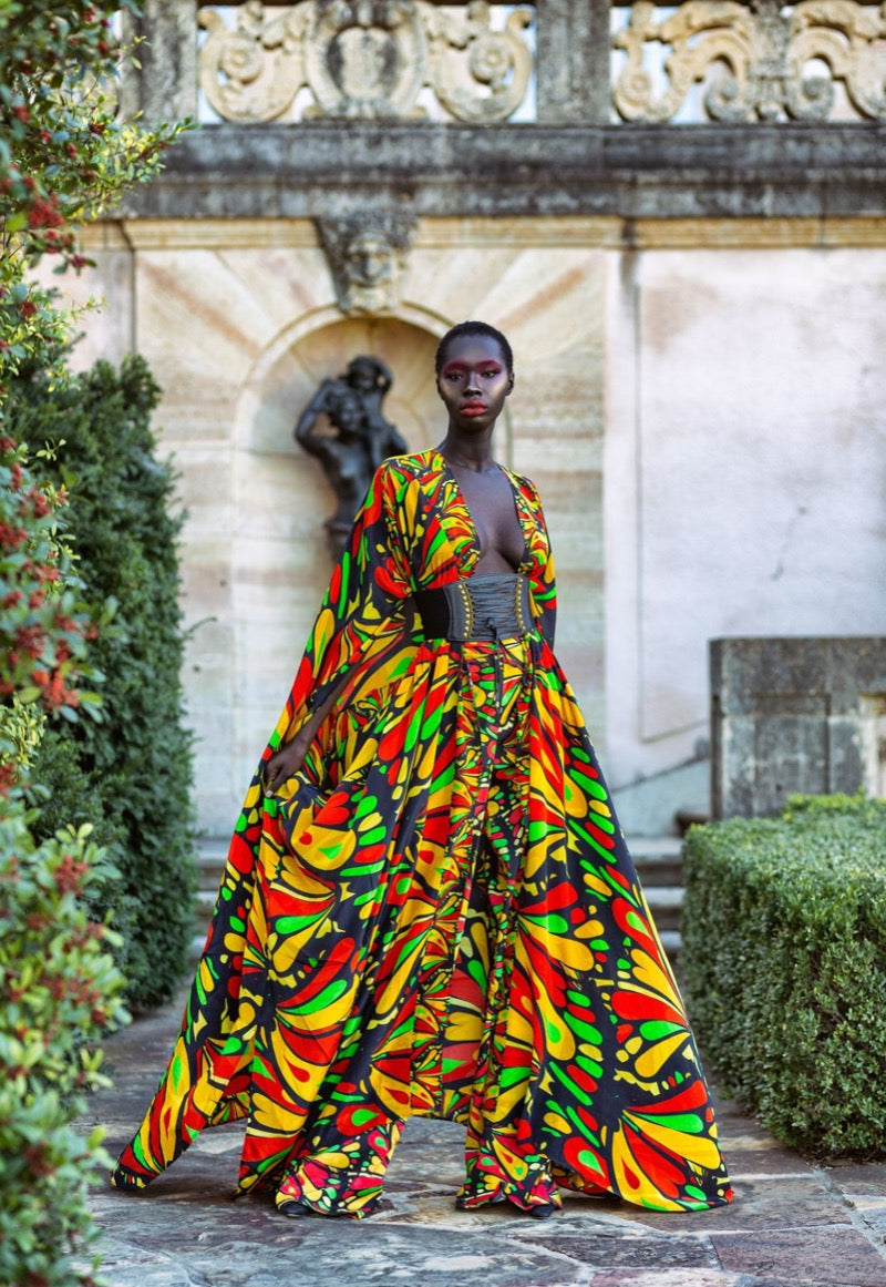 Model wearing a colorful outfit in an outdoor setting with classical architecture.