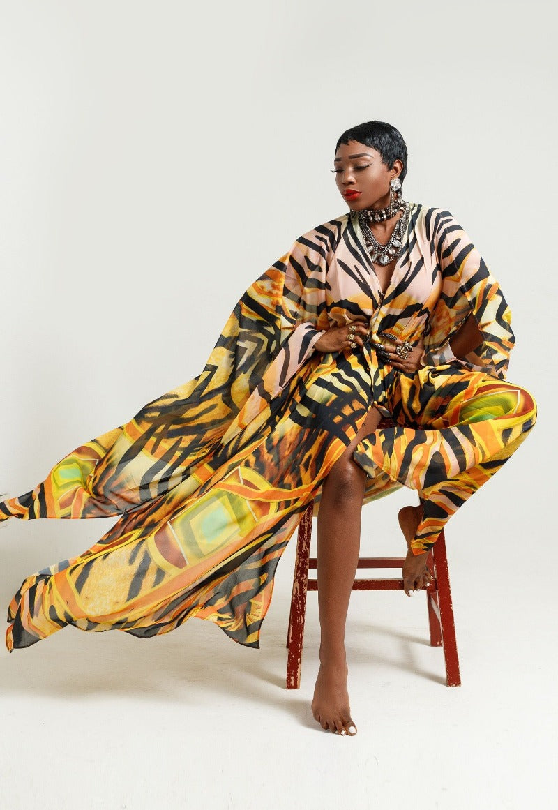 Woman in a colorful, patterned outfit sitting on a chair against a white background