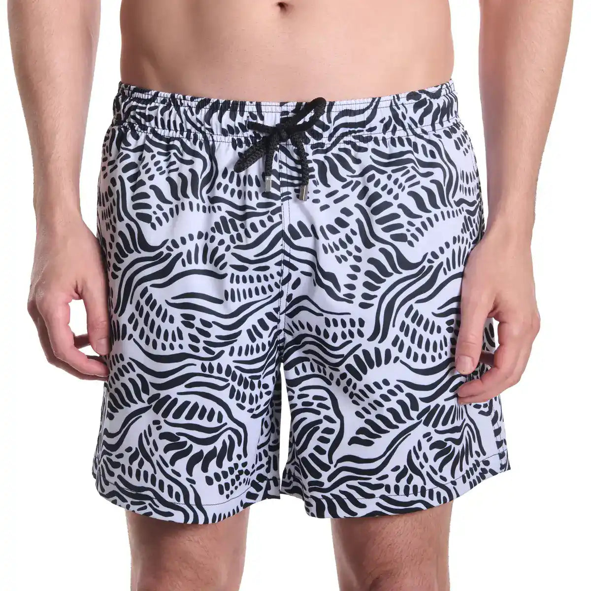 Black and white patterned swim shorts on a person against a white background