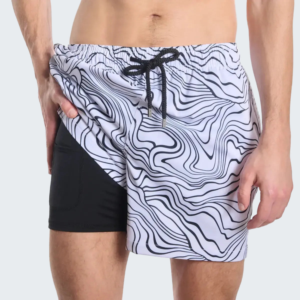 Person wearing a black and white patterned swim shorts on a white background
