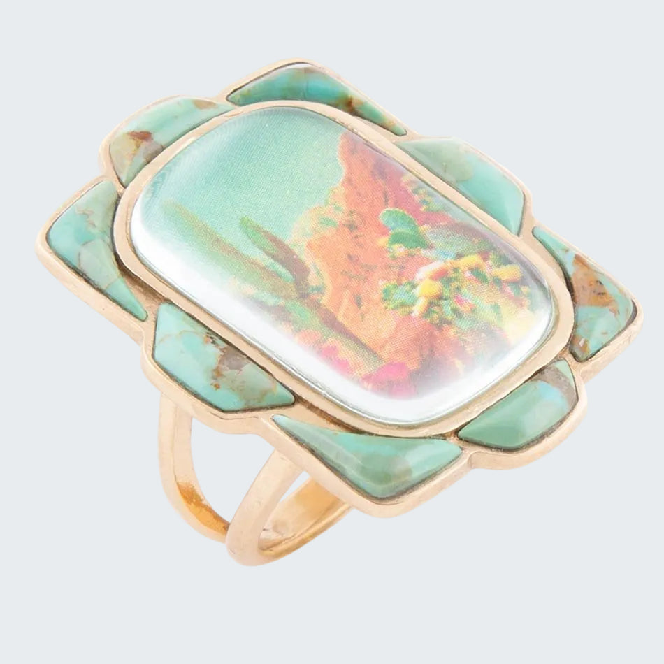 Ring with a large, colorful stone and gold band on a white background