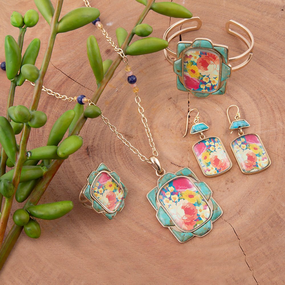 Jewelry set with floral designs on a wooden surface with green leaves.