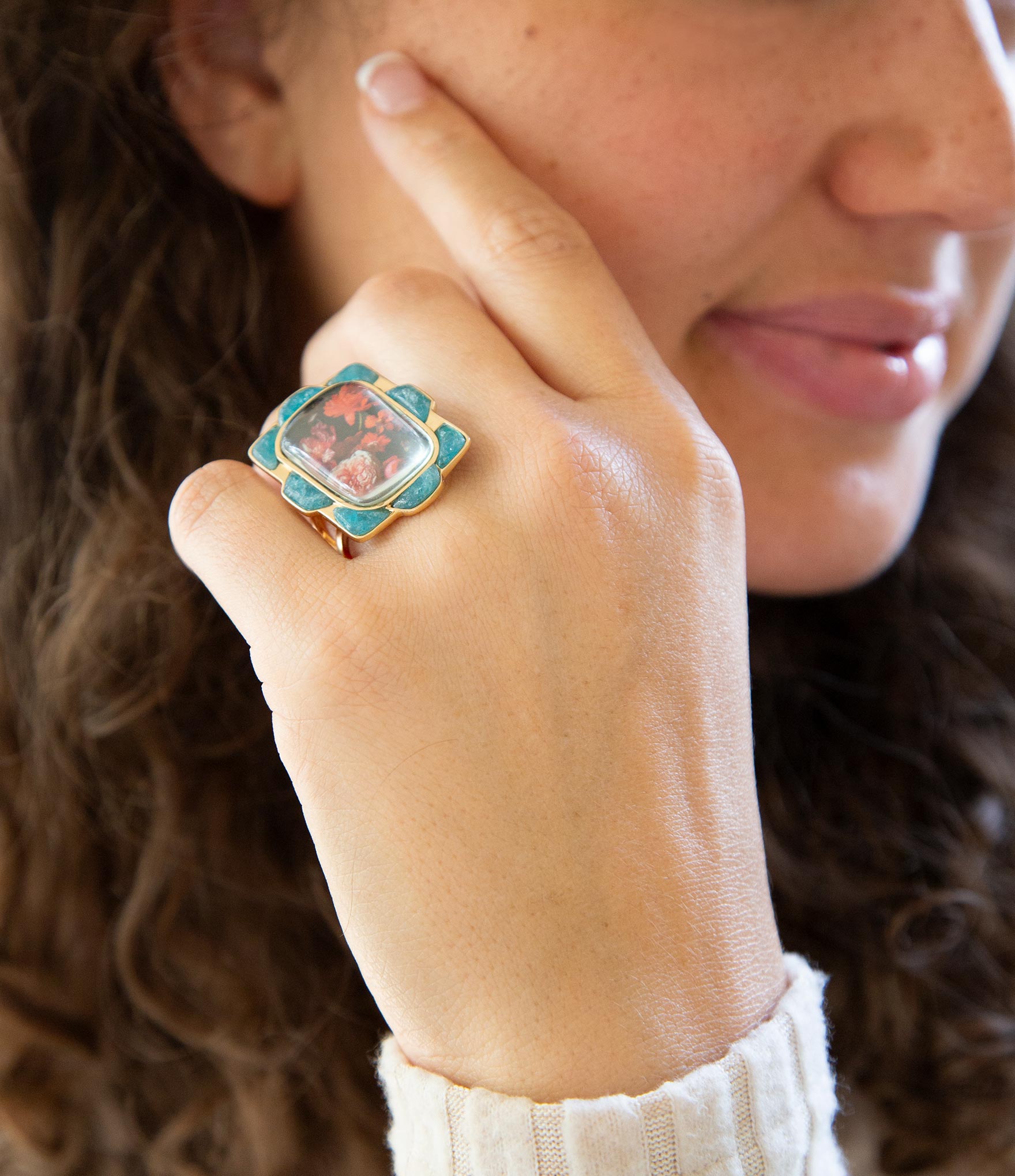 Close-up of a woman's hand wearing a decorative ring with a floral design.