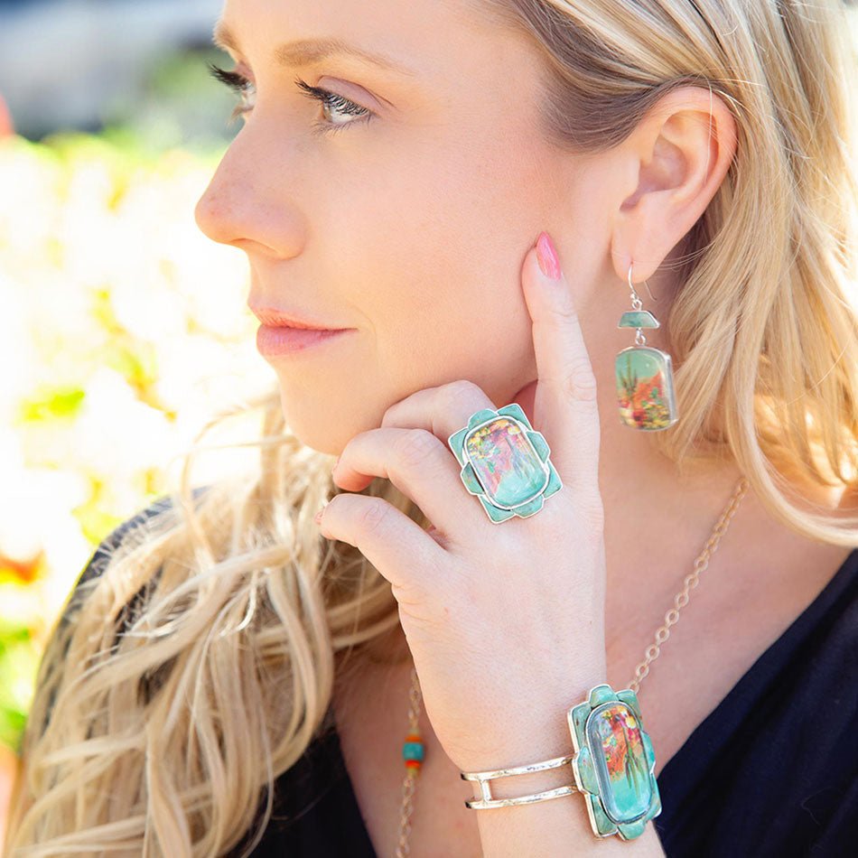 Woman wearing colorful earrings and a ring with a blurred outdoor background