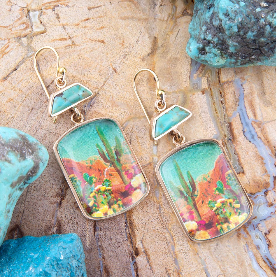 Pair of earrings with desert landscape design on a stone surface