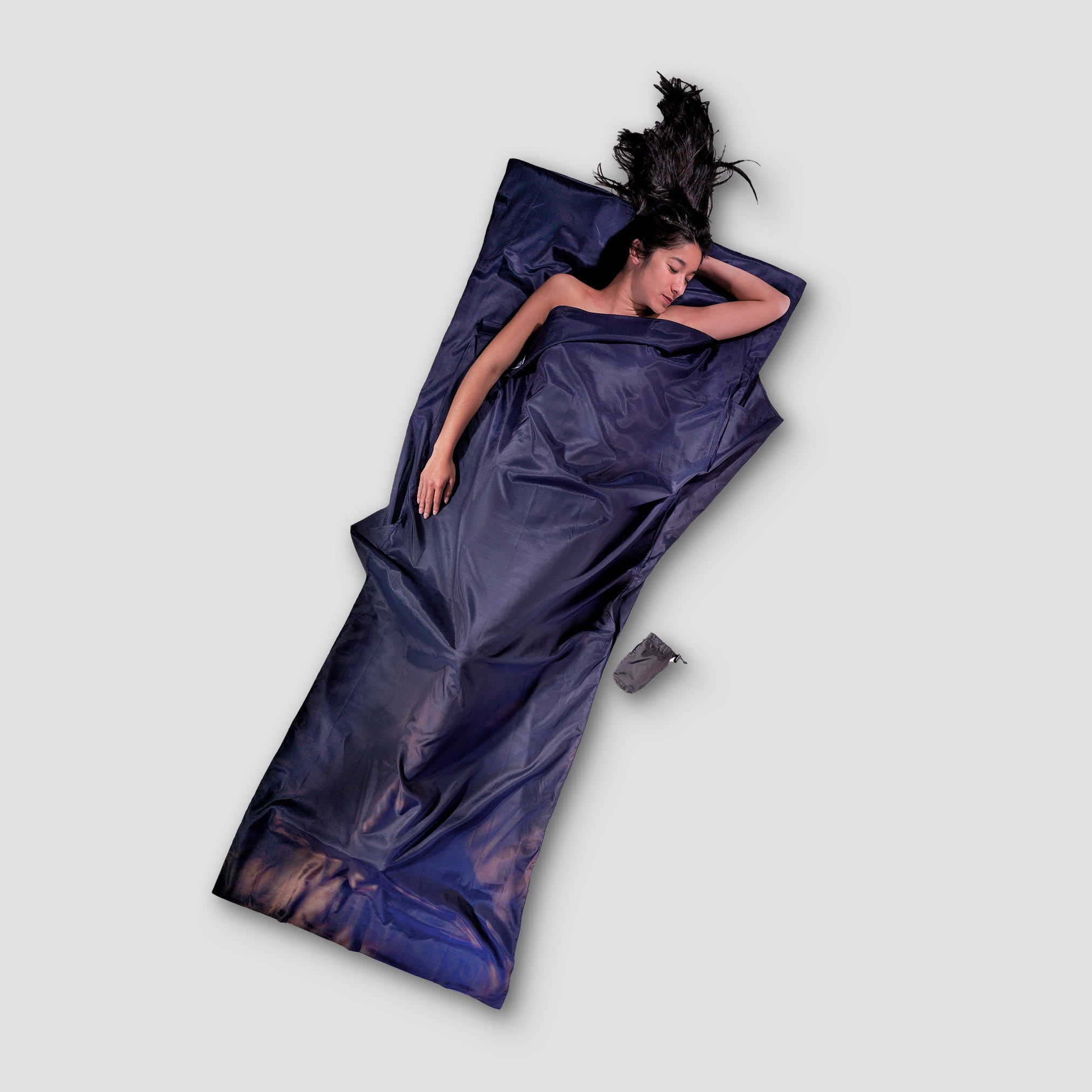 Woman lying on a purple sleeping bag with a gray background
