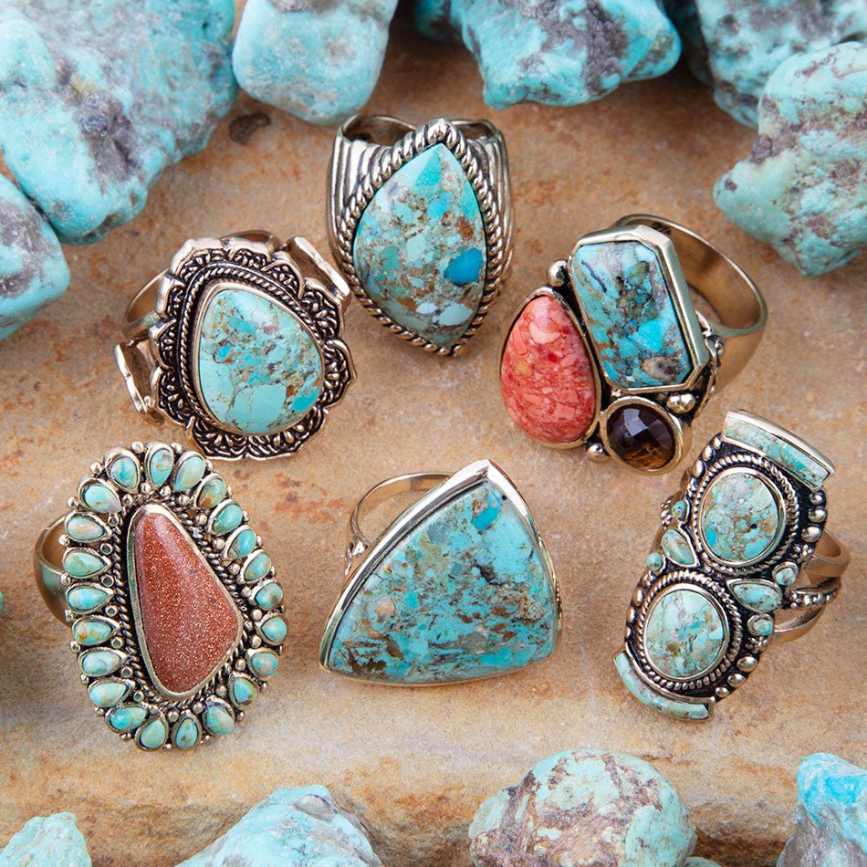 Collection of turquoise and coral rings on a stone surface with turquoise stones.