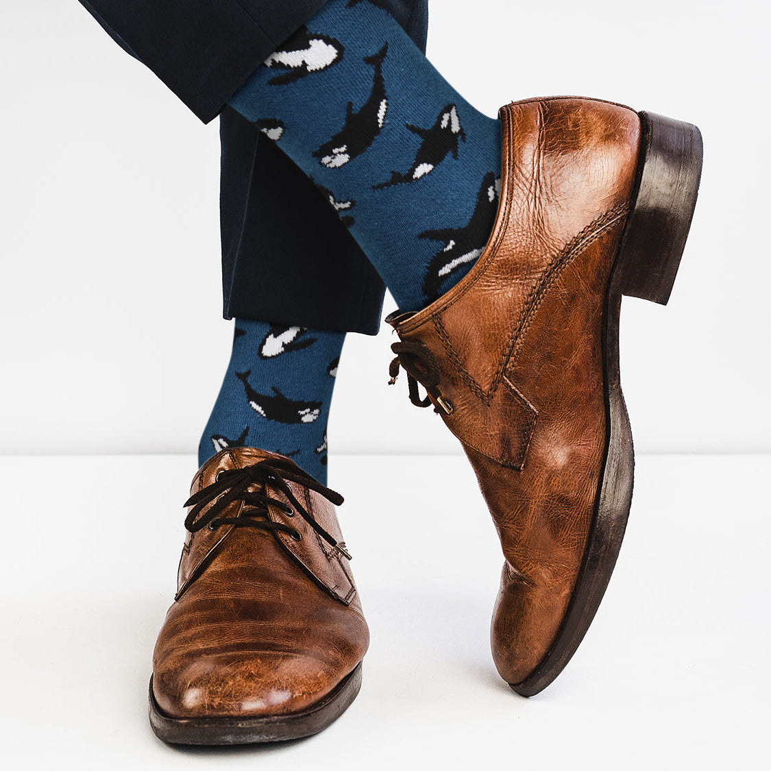 Brown dress shoes with blue socks featuring shark patterns on a white background