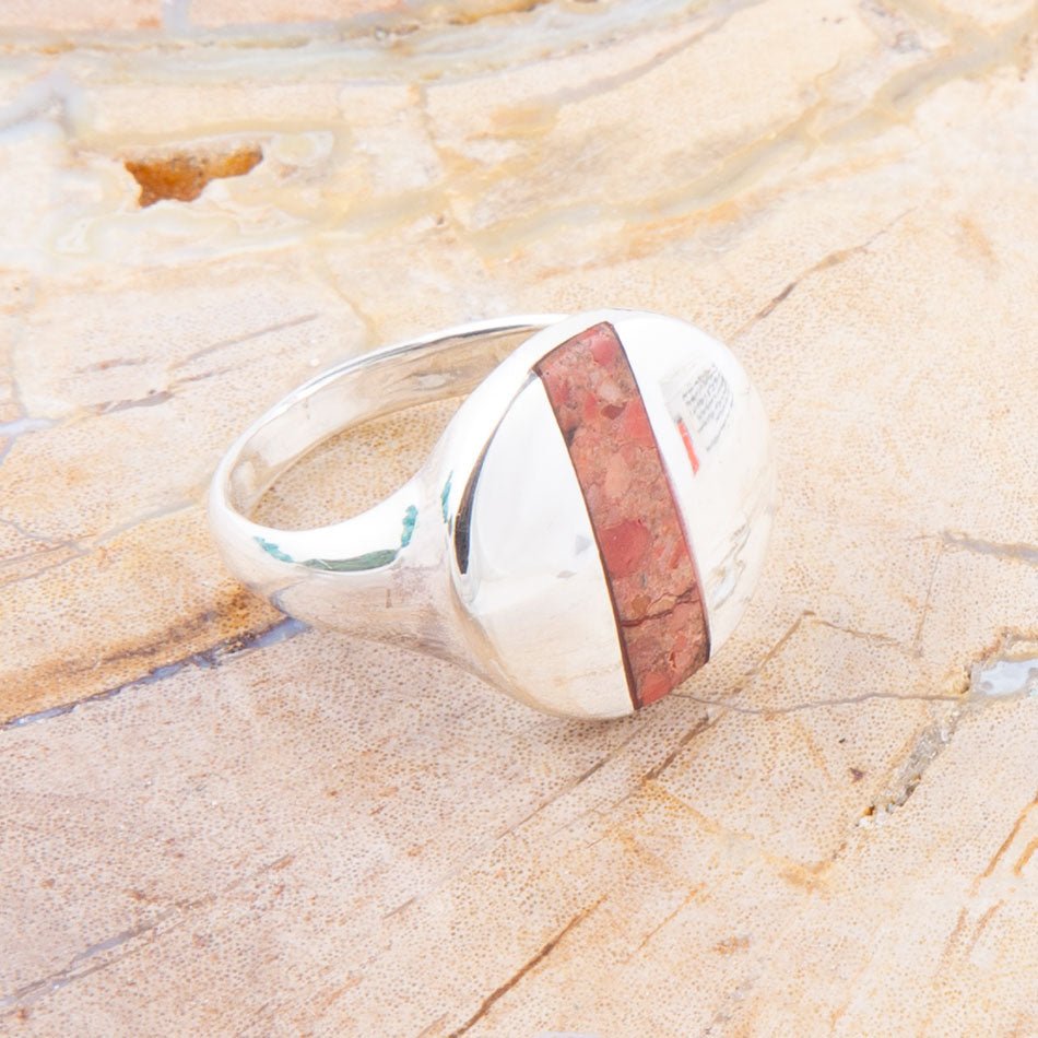 Silver ring with a red stone on a marble surface