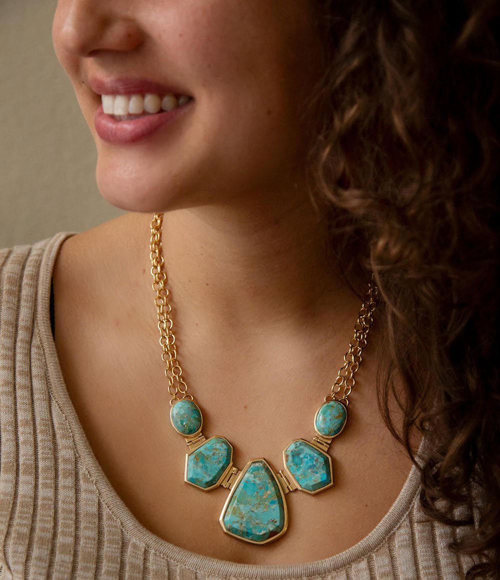 Woman wearing a gold necklace with turquoise stones