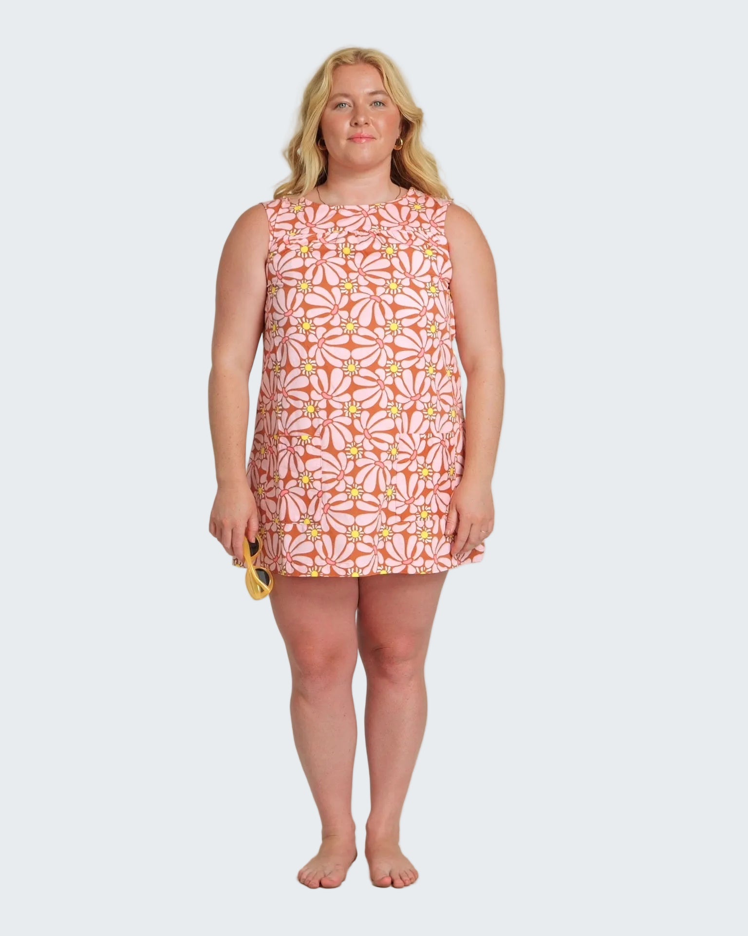 Woman wearing a sleeveless dress with a floral pattern on a white background