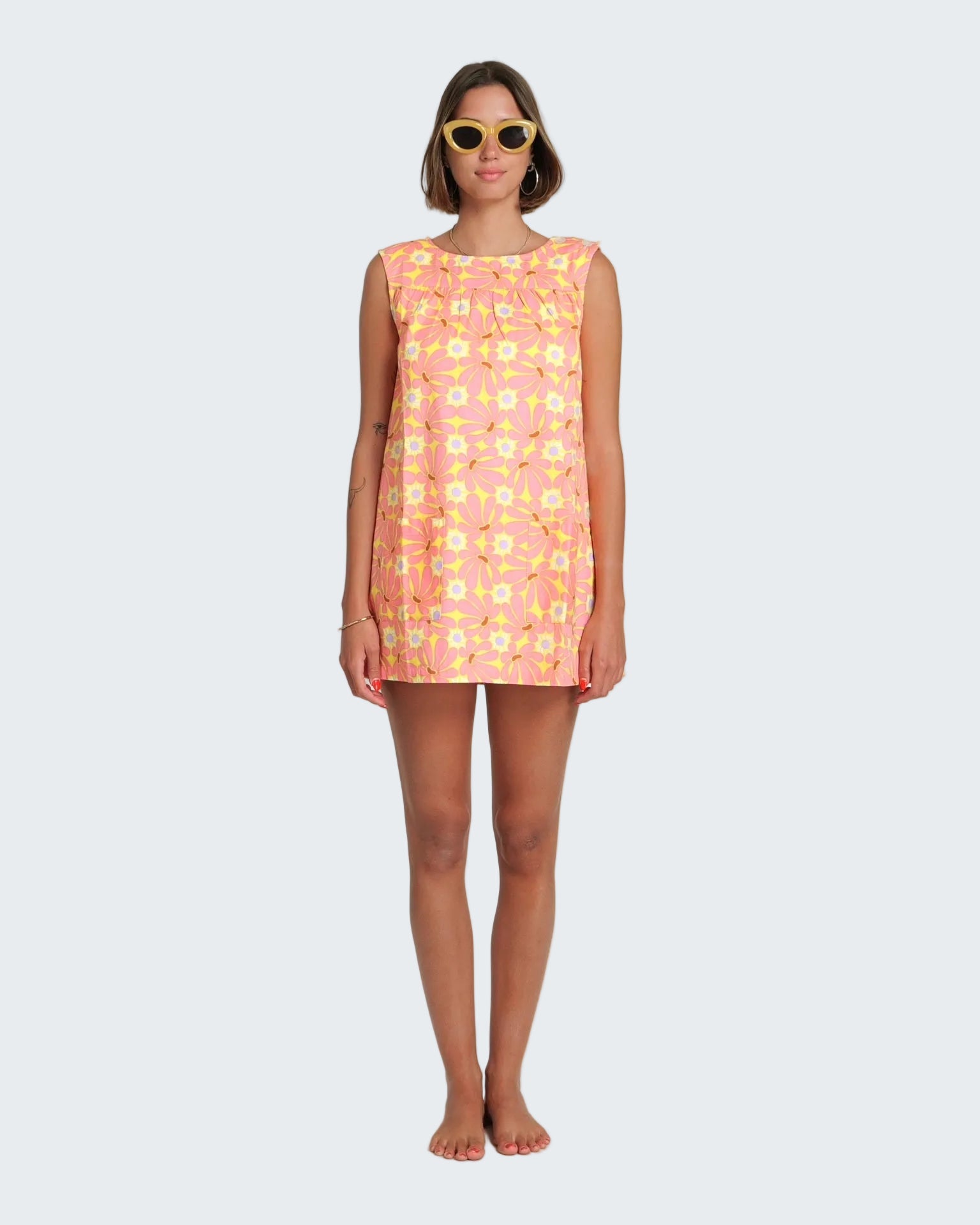 Woman wearing a sleeveless floral dress on a white background