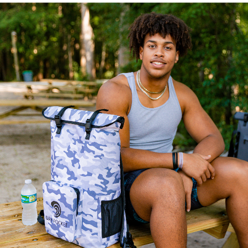 Person sitting outdoors with a blue camouflage backpack