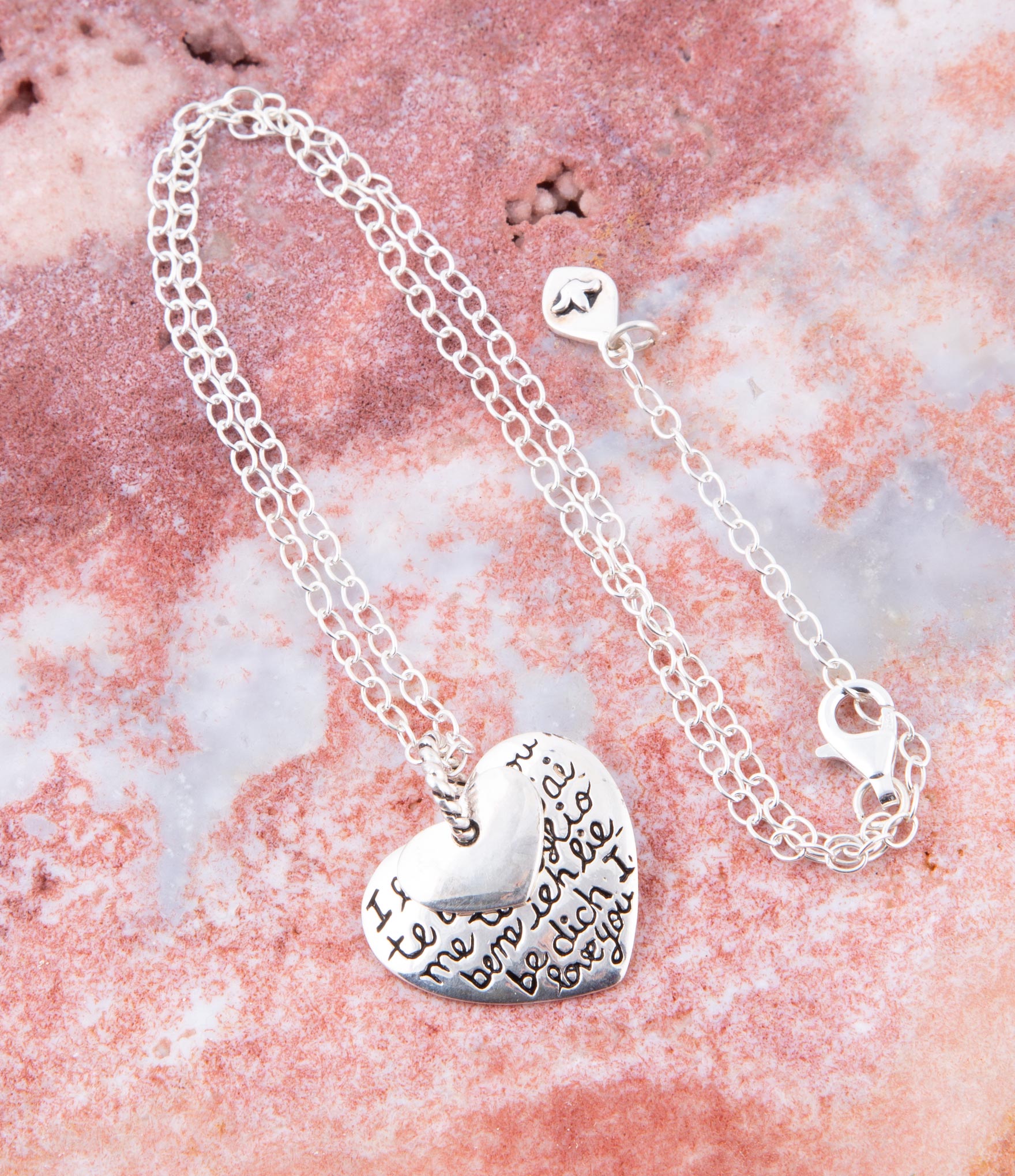 Silver heart-shaped pendant necklace on a pink marble background