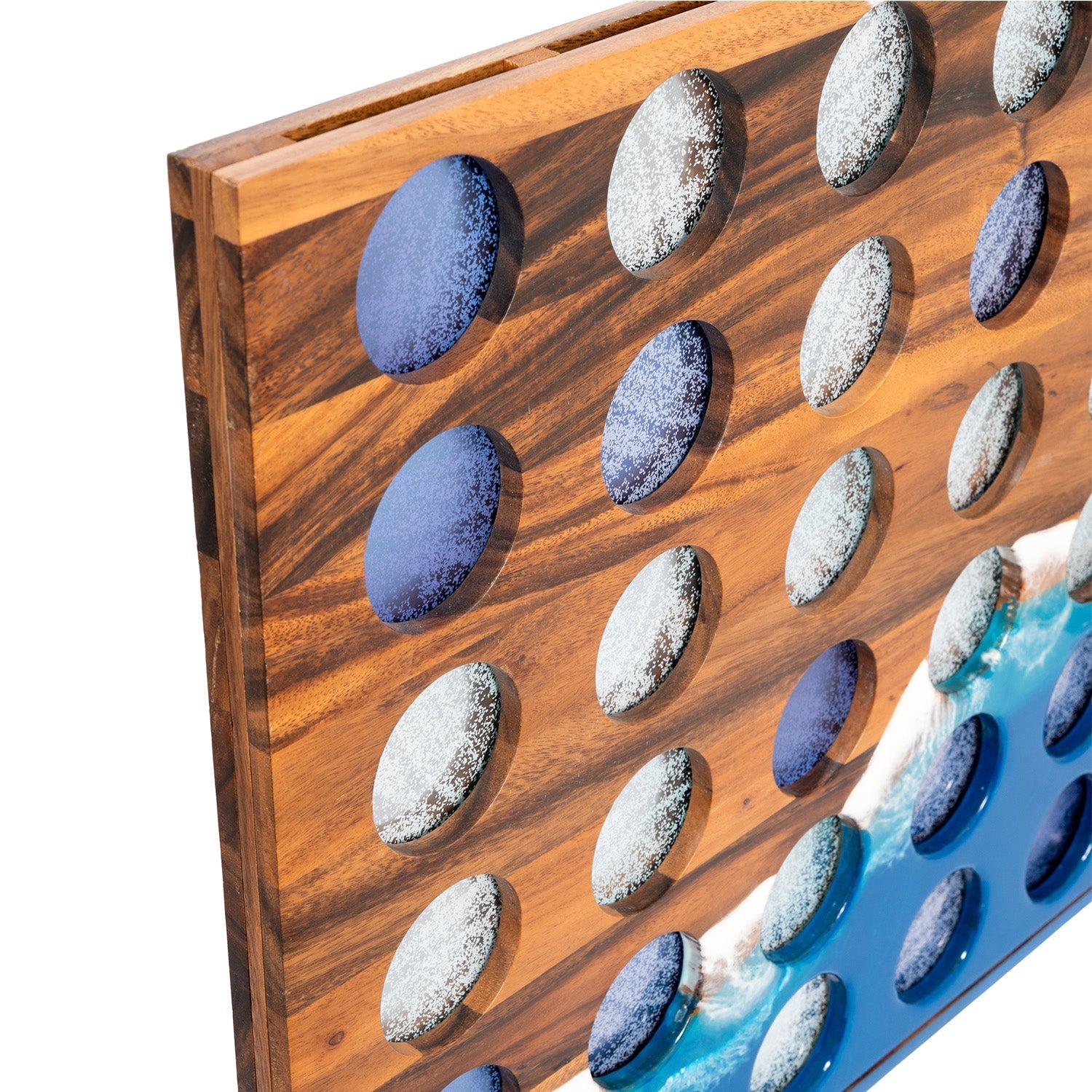 A close-up of a wooden wall art panel featuring circular cutouts filled with smooth stones in blue, gray, and white, with a blue and white wave design along the lower right edge.