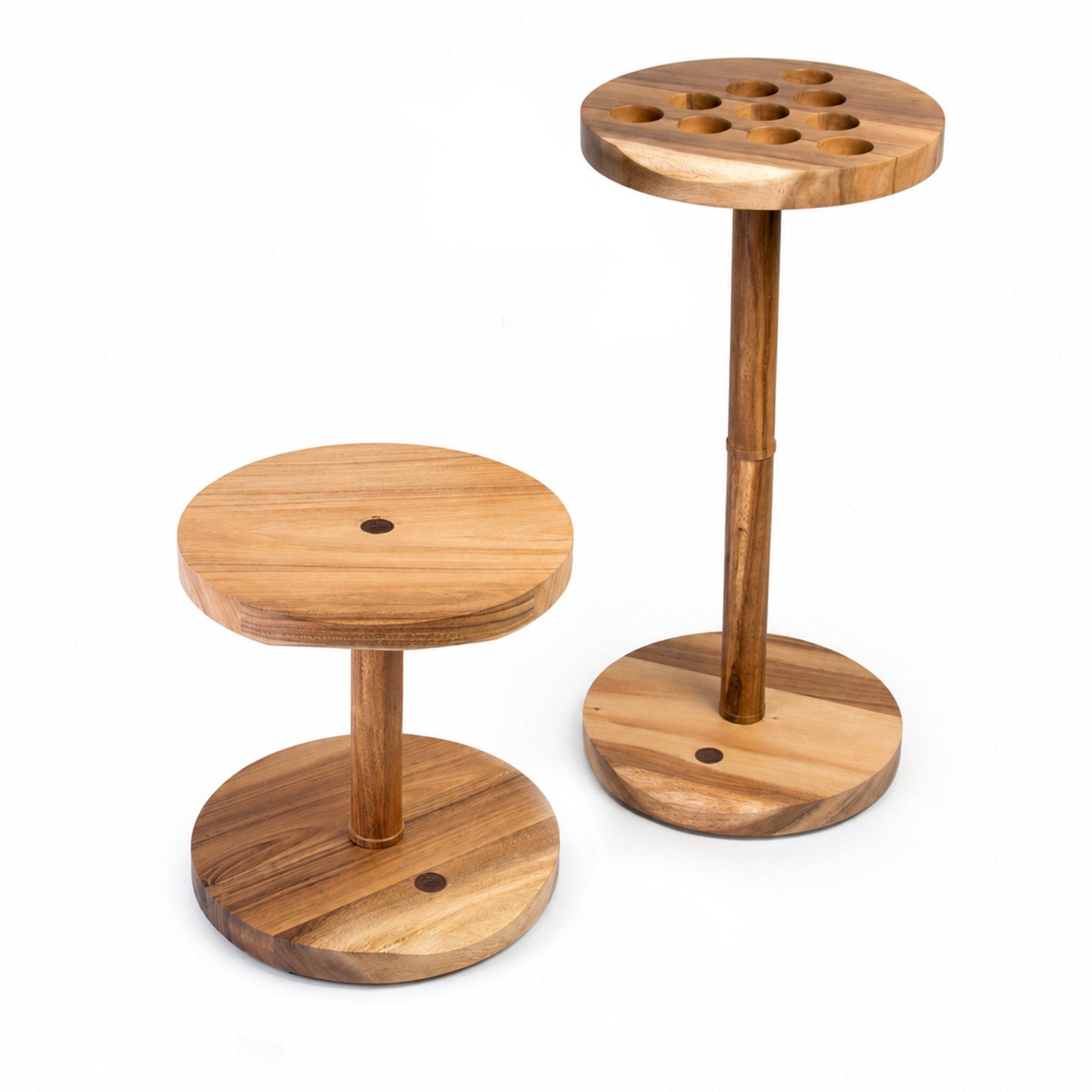 Two round wooden stools with integrated circular bases and central holes, shown on a plain white background. One stool is shorter and the other is taller, both made from light-to-medium natural wood with visible grain.
