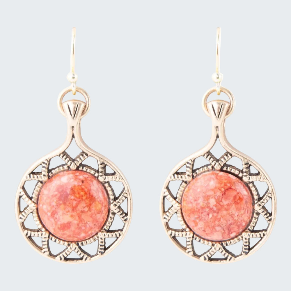 Pair of earrings with pink circular stones and gold frames on a white background