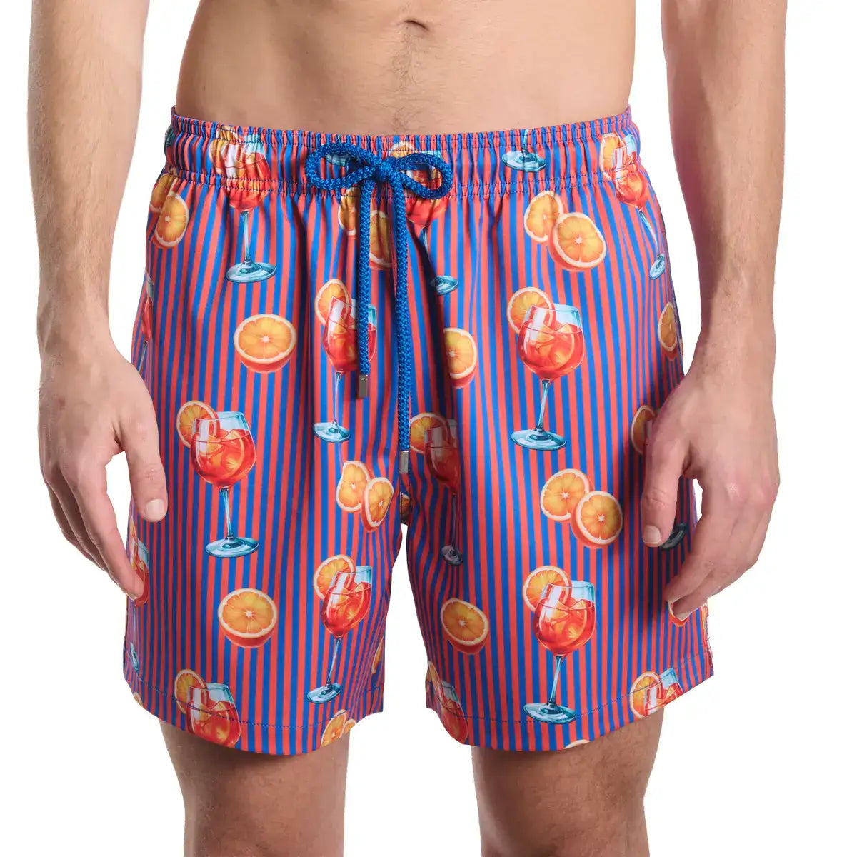 Person wearing colorful swim shorts with a drink and fruit pattern on a white background