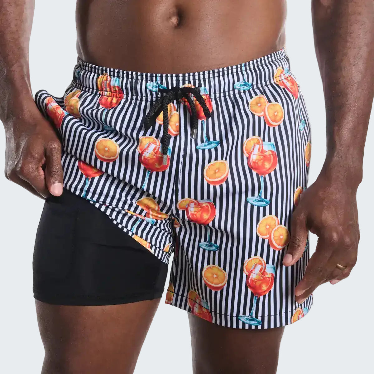 Person wearing a black and white striped swimsuit with fruit pattern on a plain background