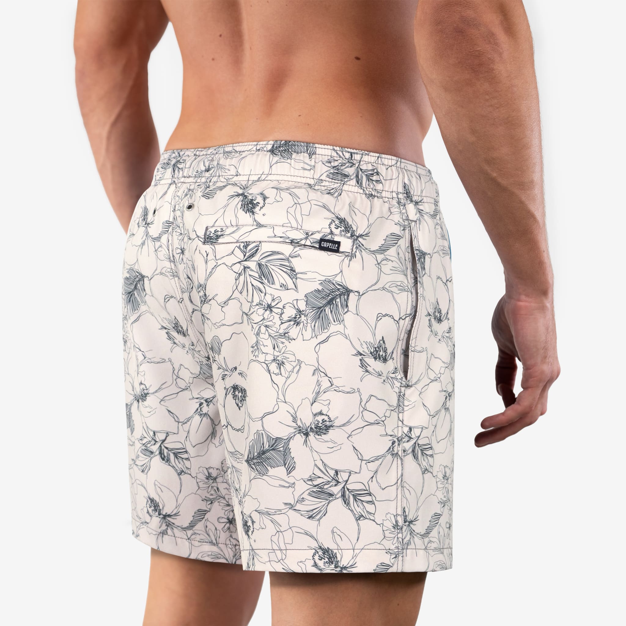Man wearing floral-patterned swim shorts on a plain background