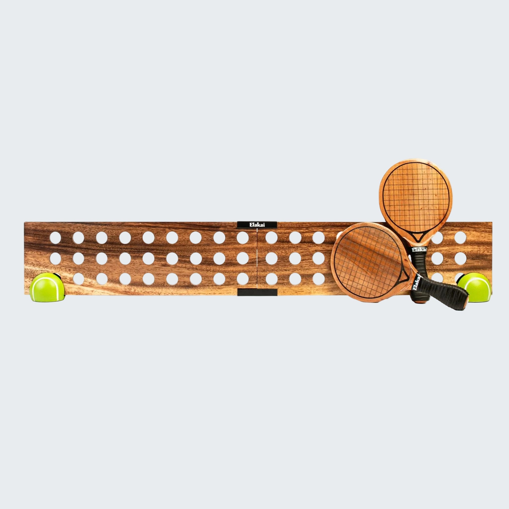 A wooden tennis paddle stand with two wooden tennis rackets resting on it, flanked by two bright yellow tennis balls, photographed against a solid white background.