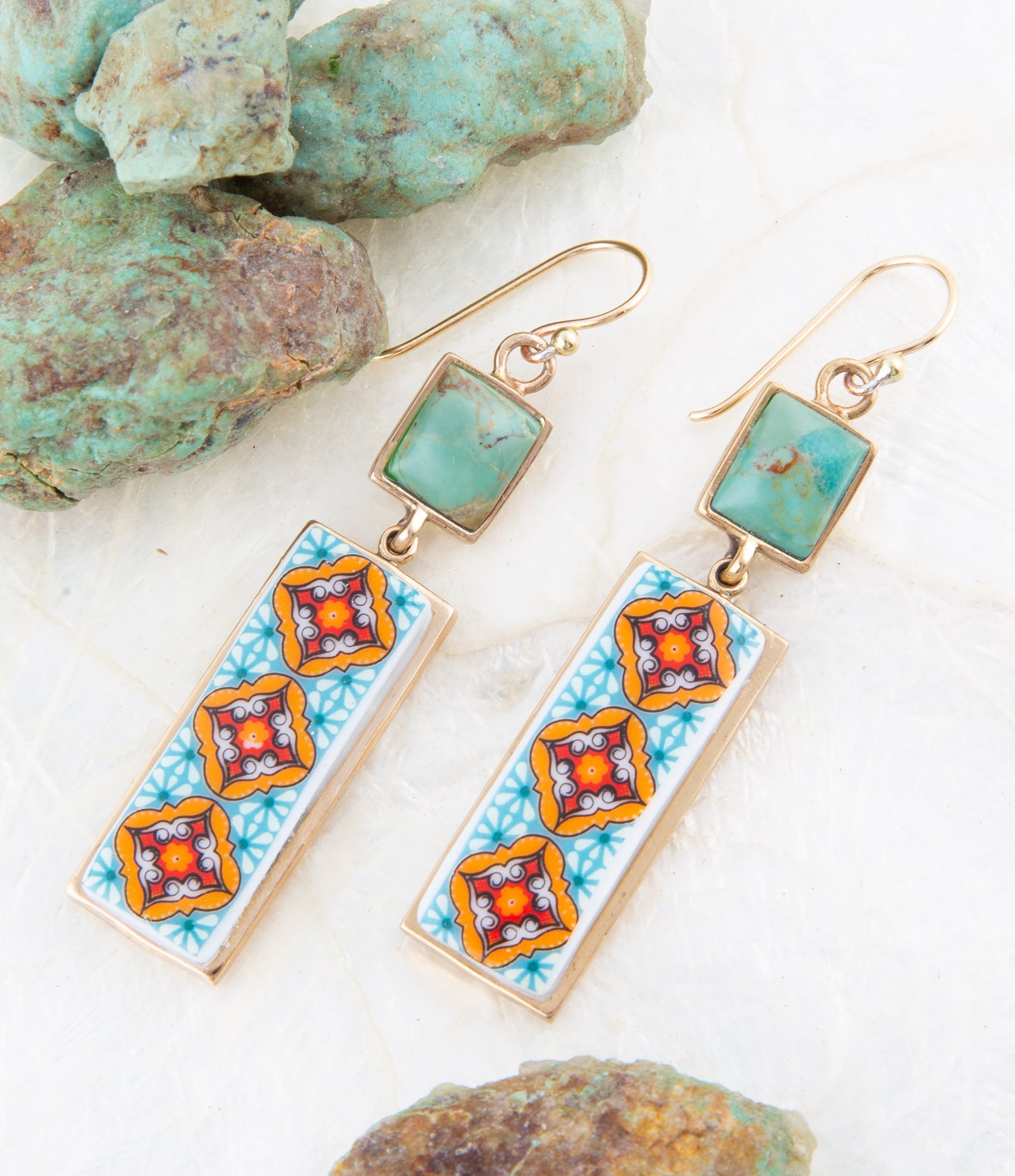 Pair of earrings with turquoise stones and colorful square designs on a white background with turquoise stones.
