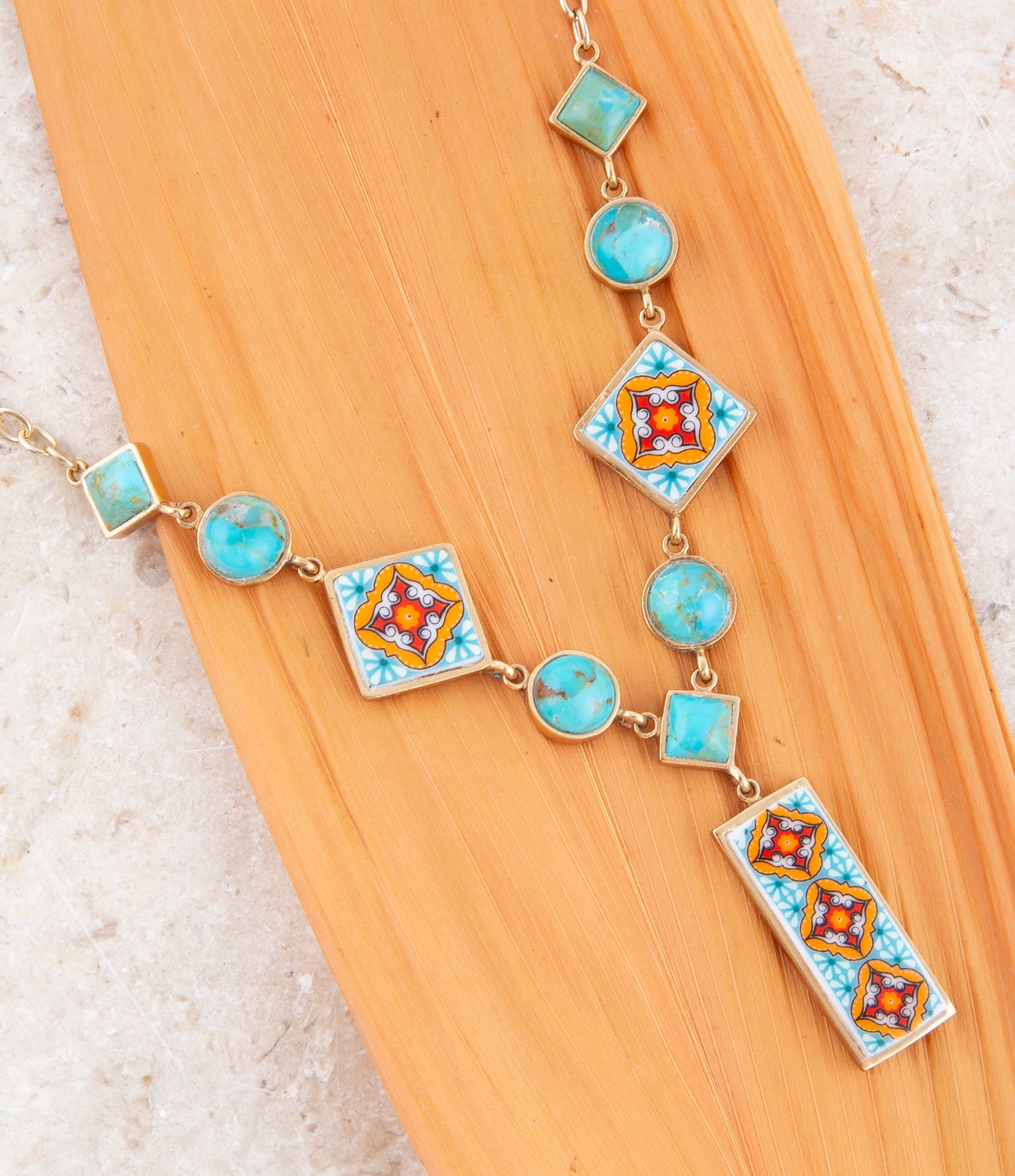 Necklace with turquoise and multicolored square pendants on a wooden surface