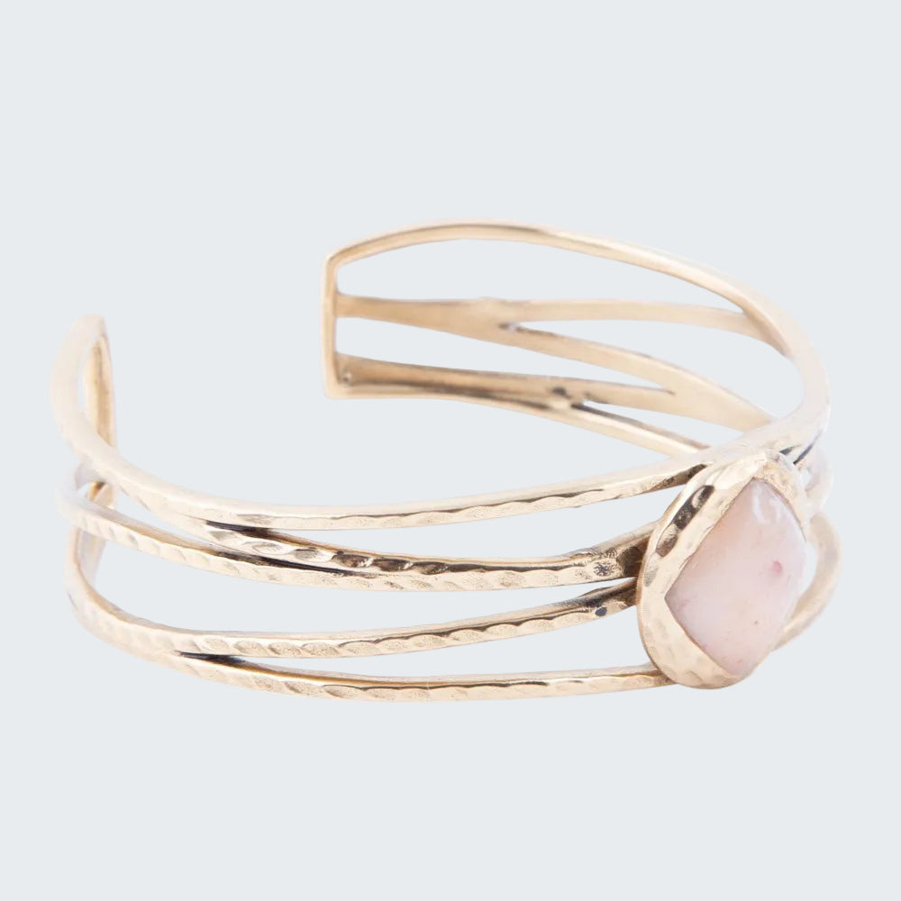 Gold bracelet with a pink stone on a white background