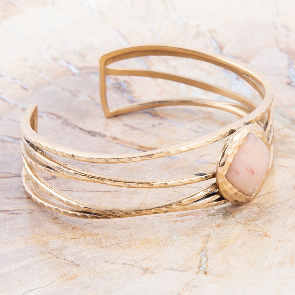 Gold bracelet with a stone on a marble surface
