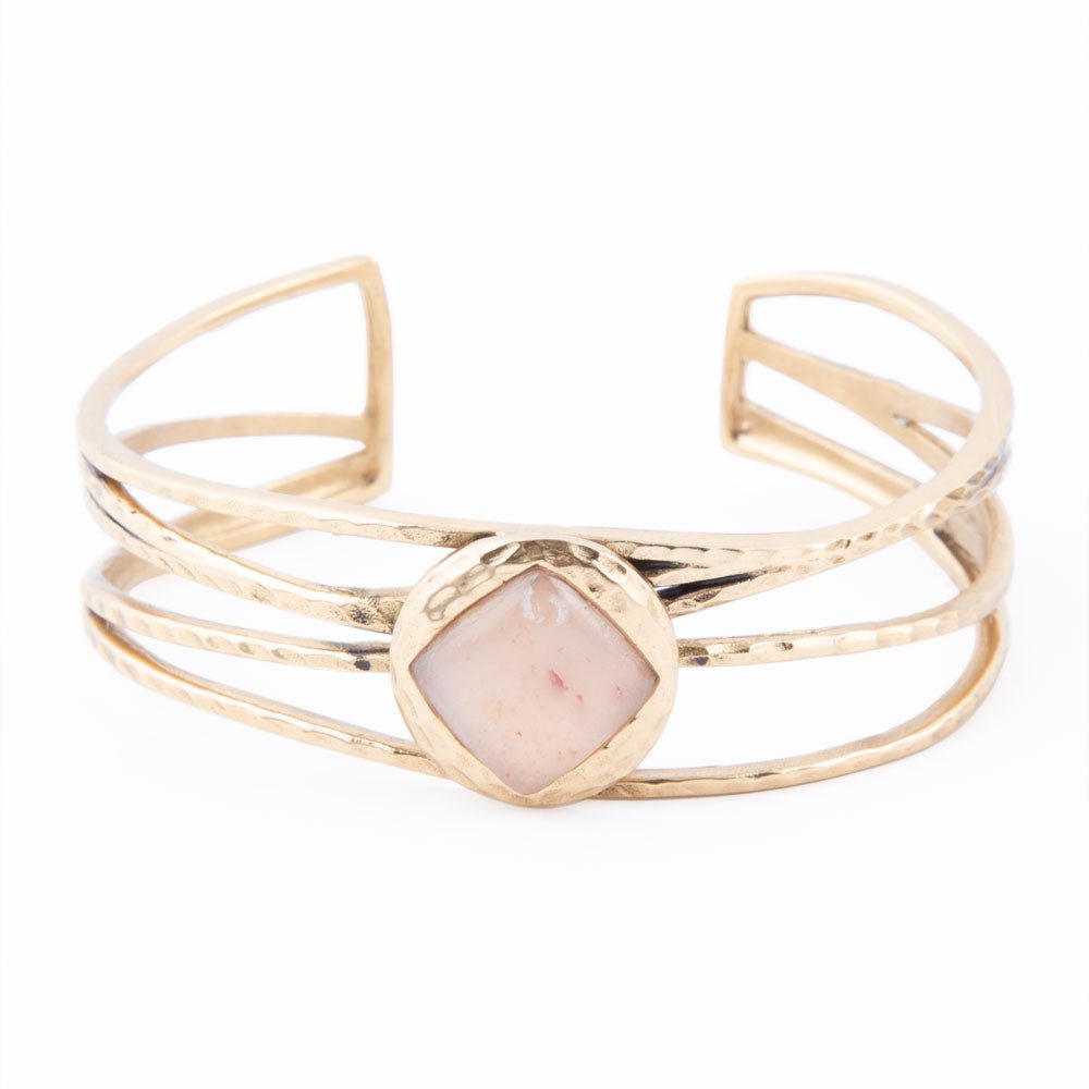 Gold bracelet with a central pink stone on a white background