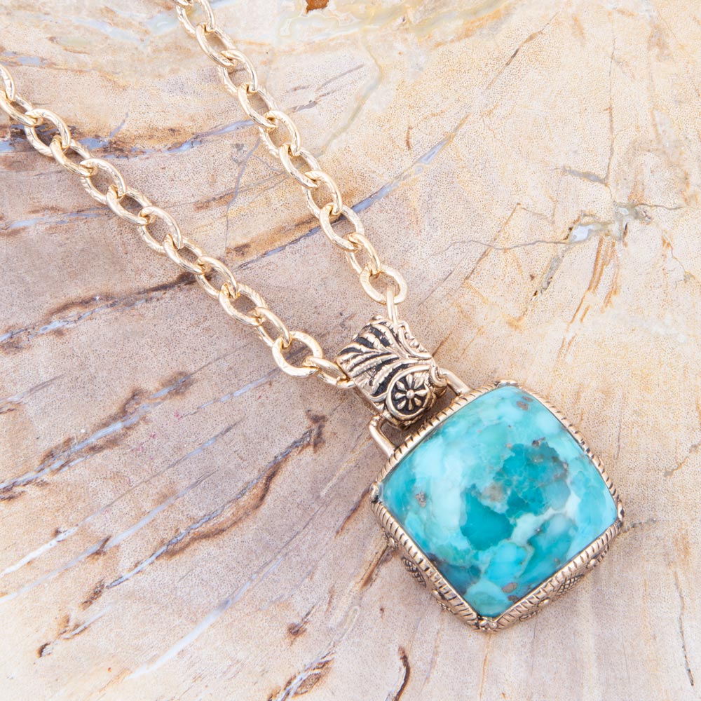 Turquoise pendant necklace on a textured beige surface