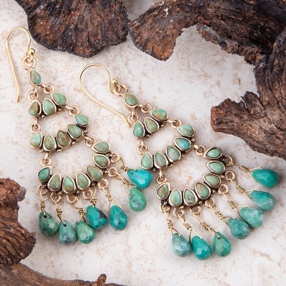 Turquoise earrings with gold accents on a natural wood background