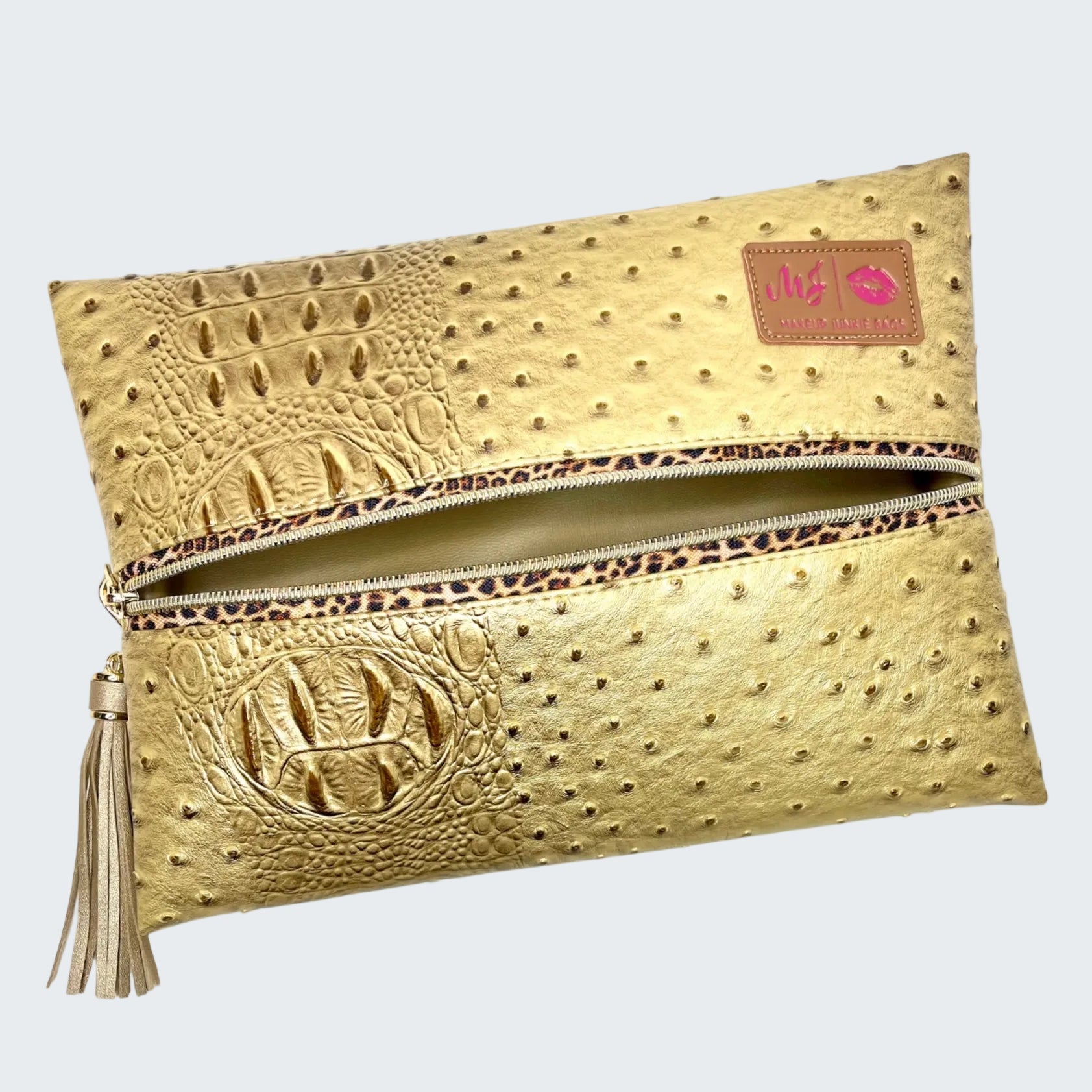 Gold clutch bag with embossed texture and tassel on a white background