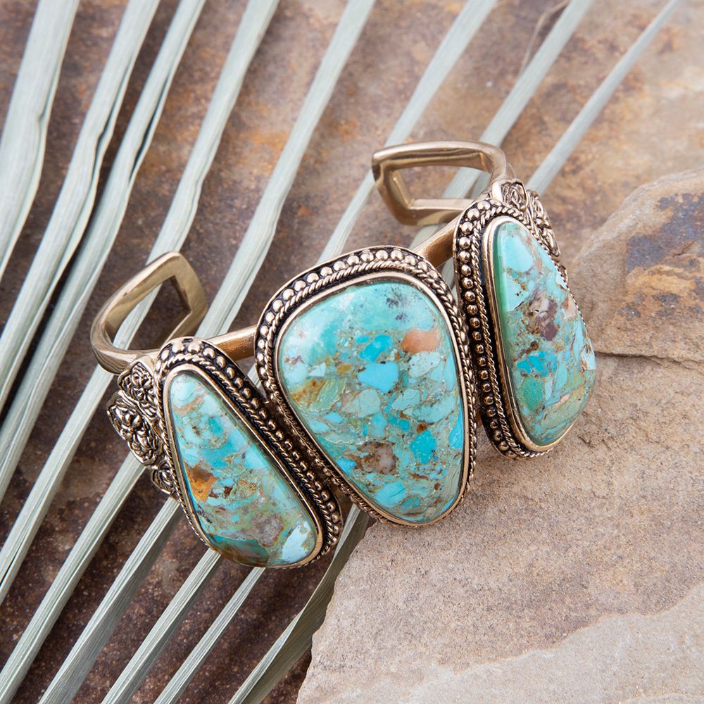 Turquoise stone bracelet with bronze accents on a textured surface